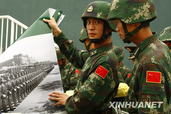 9月24日,閱兵村中的官兵在擺放“新中國歷次國慶大閱兵圖片展”展覽照片。