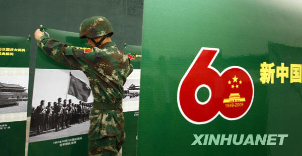 9月24日,一名閱兵村中的士兵在擺放“新中國歷次國慶大閱兵圖片展”展覽照片。