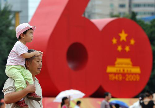 10月1日,一位市民帶著孩子經過福州街頭的新中國成立60周年國慶慶;顒訕酥。十一長假期間,各地國慶游園活動中、廣場綠地上隨處可見孩子們的可愛身影。對純真的兒童而言,十一是祖國母親的生日,也是他們的快樂假期。新華社記者 姜克紅攝